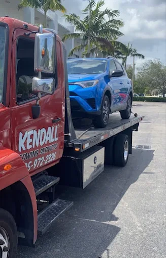 Kendall Towing Services flatbed truck transporting an SUV